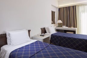 Classic double room at Candia Hotel with twin beds and blue covers plus a writing desk