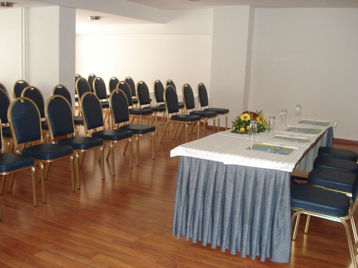 Conference room at Candia Athens conference hotel with wooden flooring, series of blue upholstered chars and speaker's station